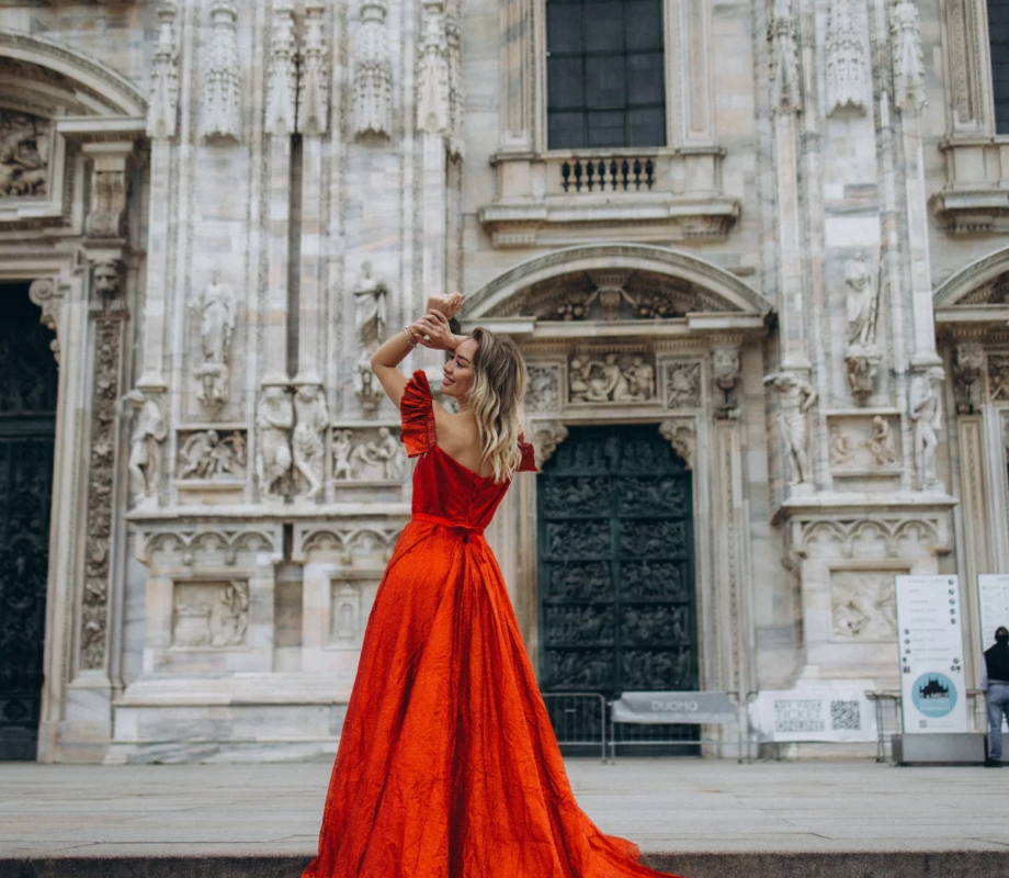 Woman in a red gown on the Duomo steps with her train cascading down, Milan