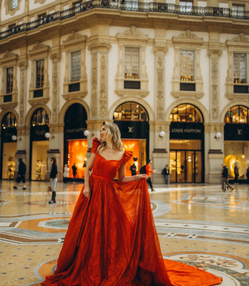 Woman in a sparkling red gown on the mosaic floor beneath the glass dome of the Galleria Vittorio Emanuele II, Milan