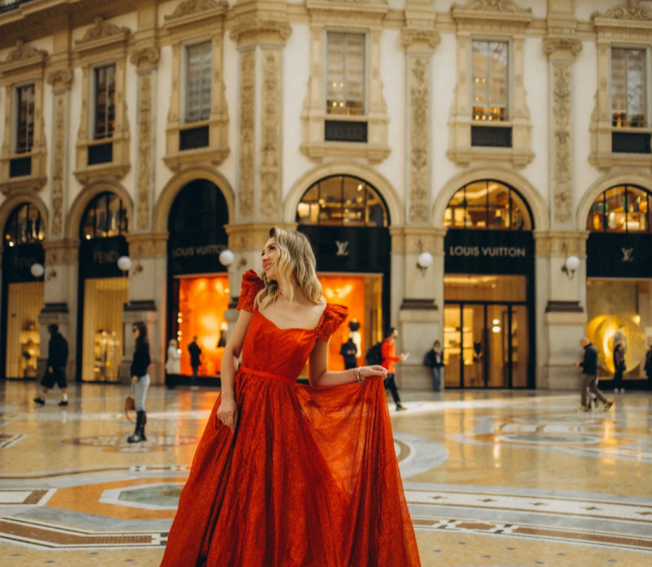 Woman in a sparkling red gown on the mosaic floor beneath the glass dome of the Galleria Vittorio Emanuele II, Milan