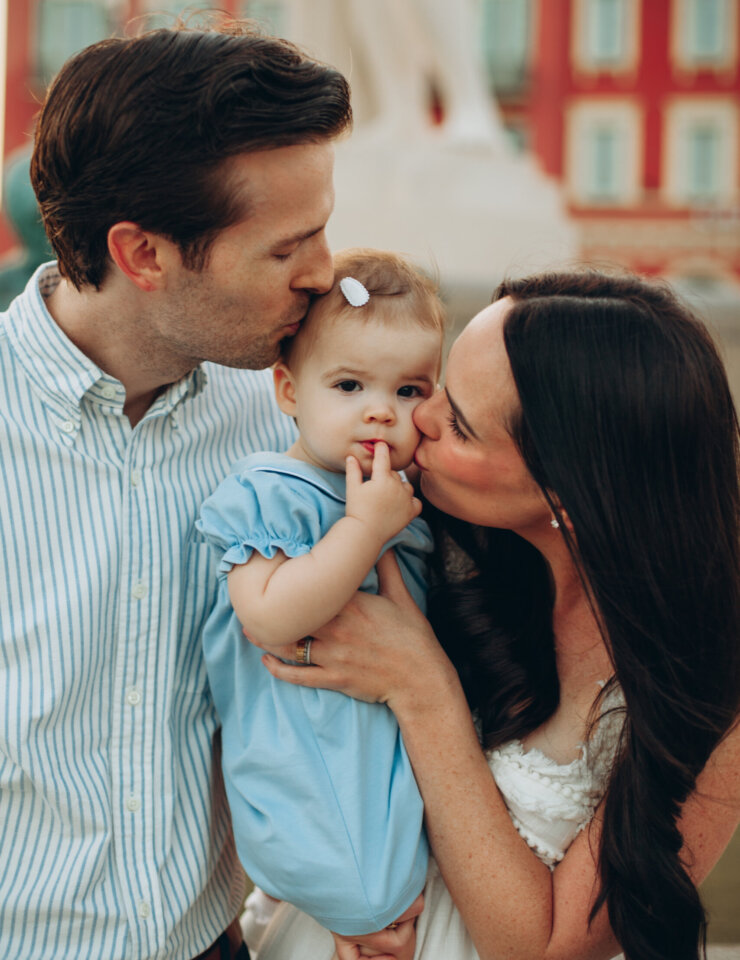 Mother and father kissing their baby daughter's cheeks in Place Masséna, Nice