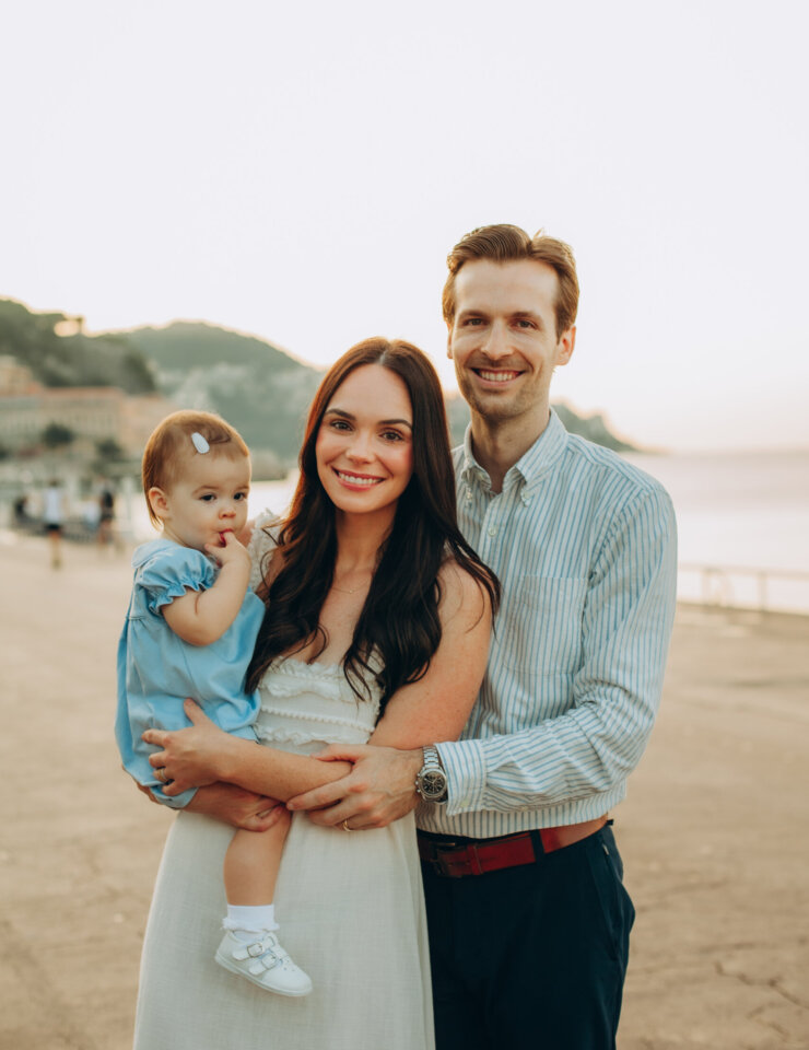 Smiling parents holding their baby on the Promenade des Anglais at soft morning light, Nice