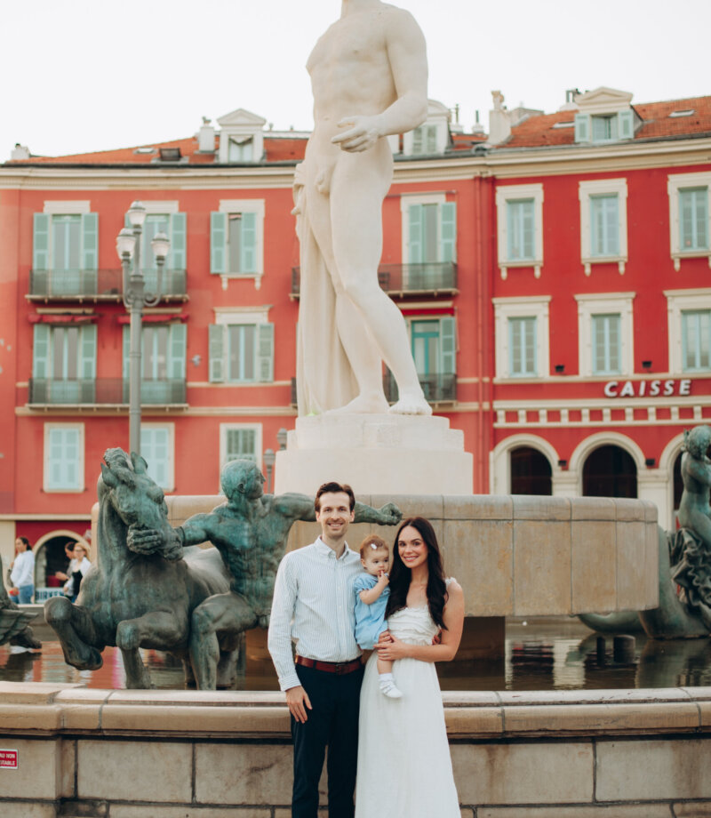Family standing at the Fontaine du Soleil with the Apollo statue in Place Masséna, Nice