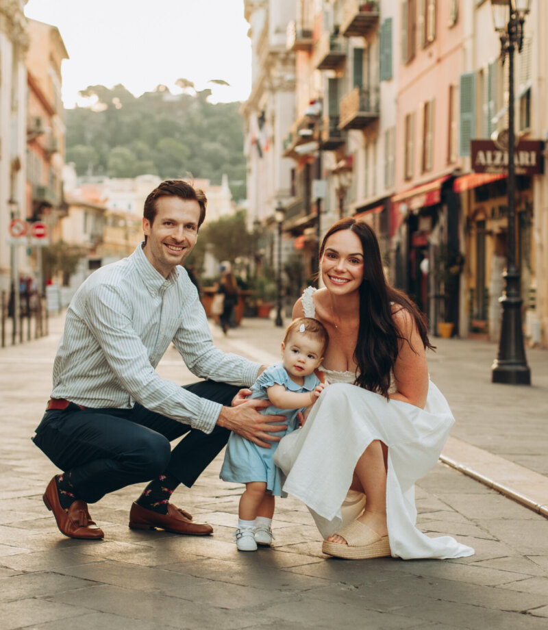 Parents crouching with their baby on an empty early-morning street in Vieux Nice