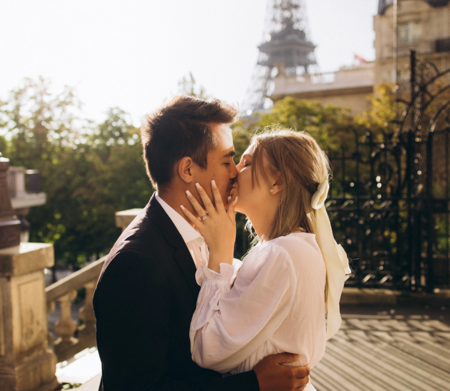 Engaged couple kissing at Avenue de Camoens with the Eiffel Tower in golden light, Paris
