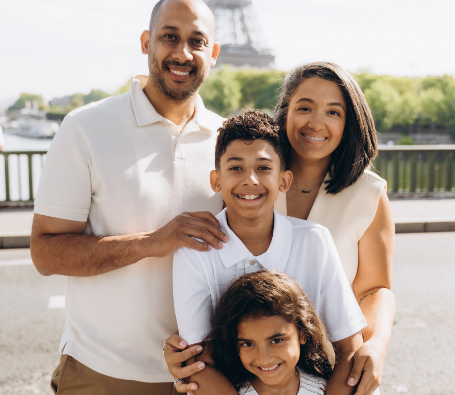 Family hugging and laughing by the Seine with the Eiffel Tower in the distance, Paris