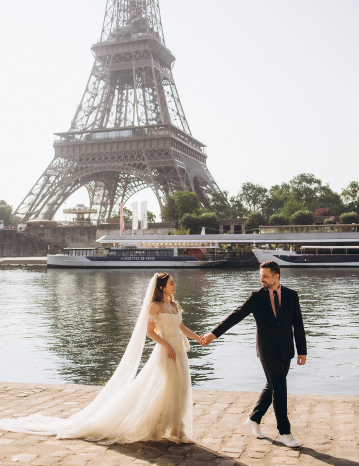 Bride and groom walking by the Seine with the Eiffel Tower behind, Paris