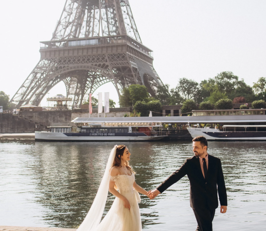 Bride and groom walking by the Seine with the Eiffel Tower behind, Paris