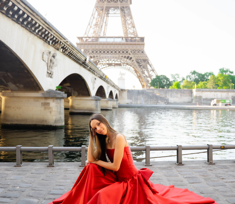 Young woman in a red ball gown on the Seine quay below Pont d'Iena and the Eiffel Tower, Paris