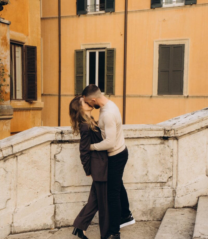 Couple on a balustrade below an orange palazzo near the Spanish Steps, Rome
