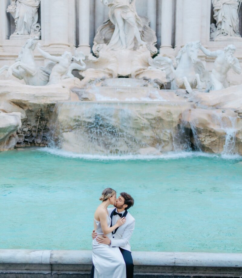 Couple in wedding clothes embracing at the Trevi Fountain early in the morning, Rome