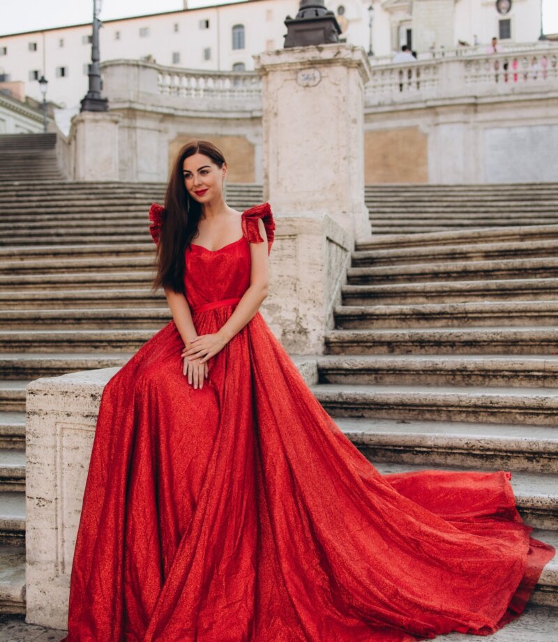 Woman in a red gown sitting on the Spanish Steps with her train spread over the stairs, Rome