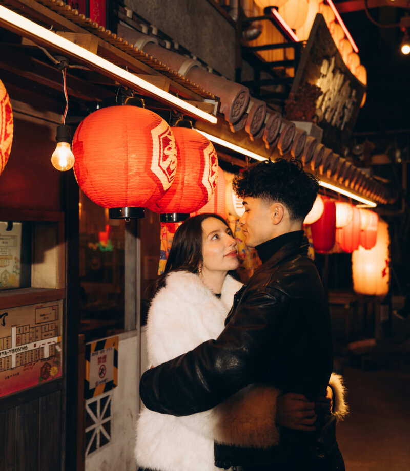 Couple hugging under red paper lanterns outside an izakaya in Shibuya, Tokyo, at night