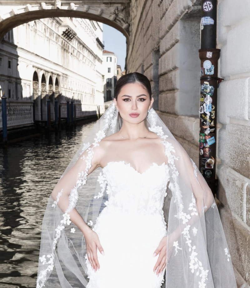 Bride in a long veil by a canal bridge, Venice