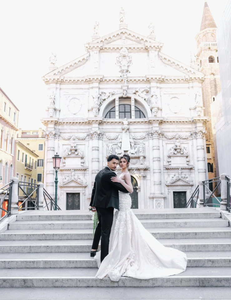 Bride and groom on the white marble steps of a Venetian church, Venice